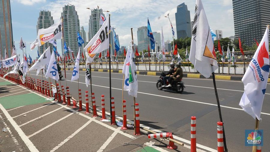 Kendaraan bermotor melintas di samping alat peraga kampanye (APK) pemilu 2024 yang terpasang di pembatas jalur sepeda (stick cone) di kawasan Menteng, Jakarta, Selasa (9/1/2024). Pemasangan APK Pemilu 2024 tersebut melanggar Peraturan KPU yang melarang pemasangan atribut partai atau caleg di fasilitas umum. (CNBC Indonesia/Muhammad Sabki)