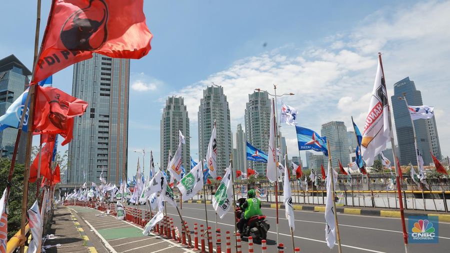 Kendaraan bermotor melintas di samping alat peraga kampanye (APK) pemilu 2024 yang terpasang di pembatas jalur sepeda (stick cone) di kawasan Menteng, Jakarta, Selasa (9/1/2024). Pemasangan APK Pemilu 2024 tersebut melanggar Peraturan KPU yang melarang pemasangan atribut partai atau caleg di fasilitas umum. (CNBC Indonesia/Muhammad Sabki)