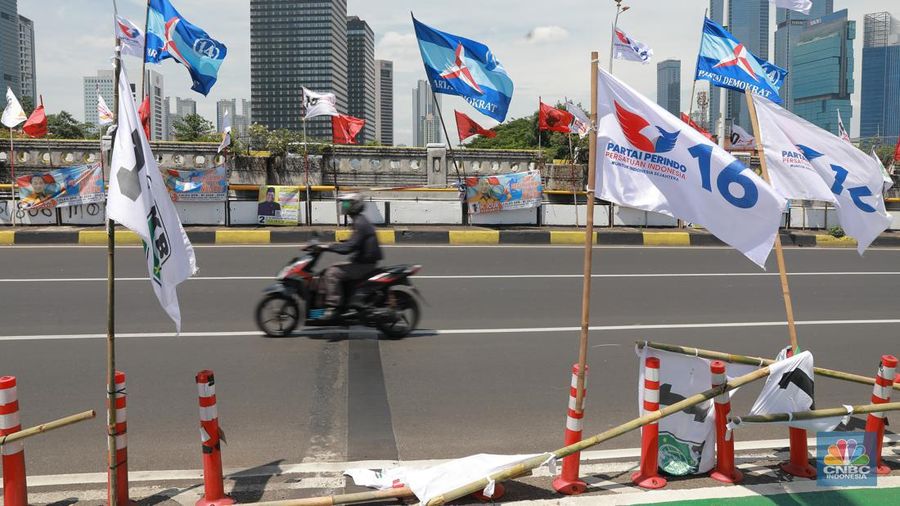 Kendaraan bermotor melintas di samping alat peraga kampanye (APK) pemilu 2024 yang terpasang di pembatas jalur sepeda (stick cone) di kawasan Menteng, Jakarta, Selasa (9/1/2024). Pemasangan APK Pemilu 2024 tersebut melanggar Peraturan KPU yang melarang pemasangan atribut partai atau caleg di fasilitas umum. (CNBC Indonesia/Muhammad Sabki)