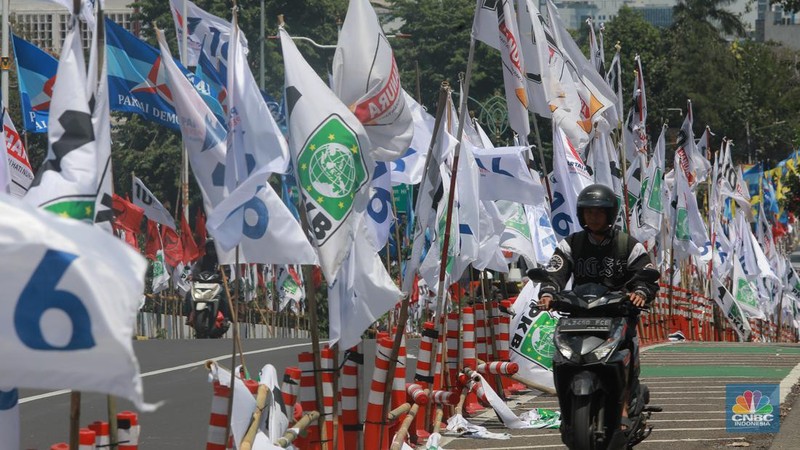 Kendaraan bermotor melintas di samping alat peraga kampanye (APK) pemilu 2024 yang terpasang di pembatas jalur sepeda (stick cone) di kawasan Menteng, Jakarta, Selasa (9/1/2024). Pemasangan APK Pemilu 2024 tersebut melanggar Peraturan KPU yang melarang pemasangan atribut partai atau caleg di fasilitas umum. (CNBC Indonesia/Muhammad Sabki)