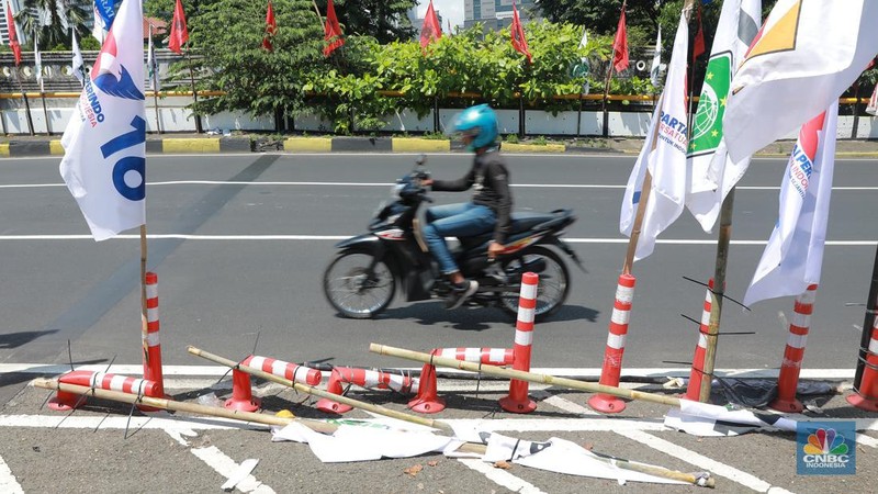 Kendaraan bermotor melintas di samping alat peraga kampanye (APK) pemilu 2024 yang terpasang di pembatas jalur sepeda (stick cone) di kawasan Menteng, Jakarta, Selasa (9/1/2024). Pemasangan APK Pemilu 2024 tersebut melanggar Peraturan KPU yang melarang pemasangan atribut partai atau caleg di fasilitas umum. (CNBC Indonesia/Muhammad Sabki)