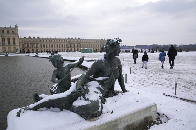 Orang-orang berjalan di gang-gang yang tertutup salju di Chateau de Versailles Selasa, 9 Januari 2024 di Versailles, sebelah barat Paris, di mana suhu turun di bawah nol derajat Celcius. (AP Photo/Christophe Ena)
