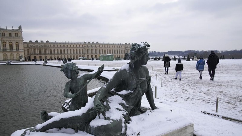 Orang-orang berjalan di gang-gang yang tertutup salju di Chateau de Versailles Selasa, 9 Januari 2024 di Versailles, sebelah barat Paris, di mana suhu turun di bawah nol derajat Celcius. (AP Photo/Christophe Ena)