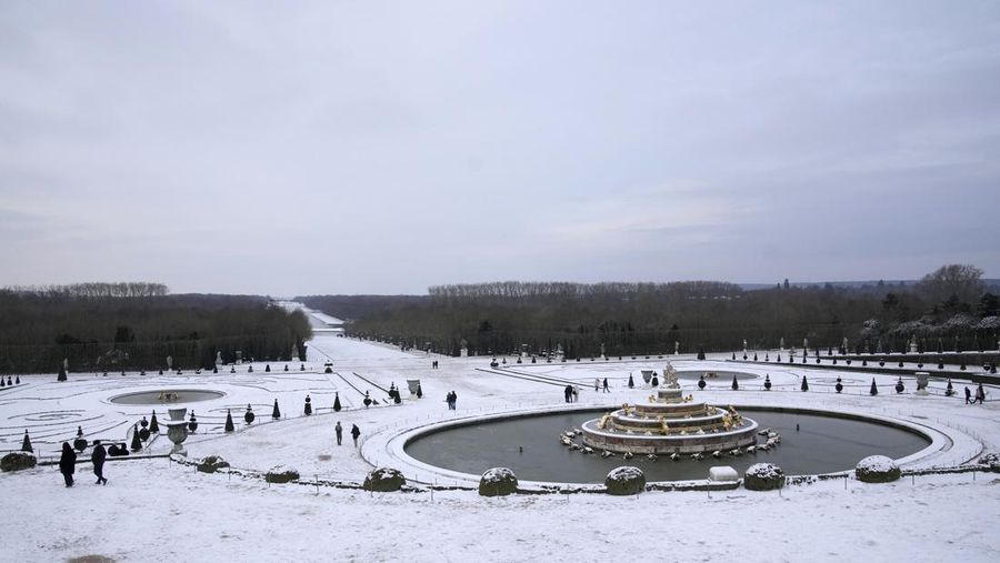 Orang-orang berjalan di gang-gang yang tertutup salju di Chateau de Versailles Selasa, 9 Januari 2024 di Versailles, sebelah barat Paris, di mana suhu turun di bawah nol derajat Celcius. (AP Photo/Christophe Ena)