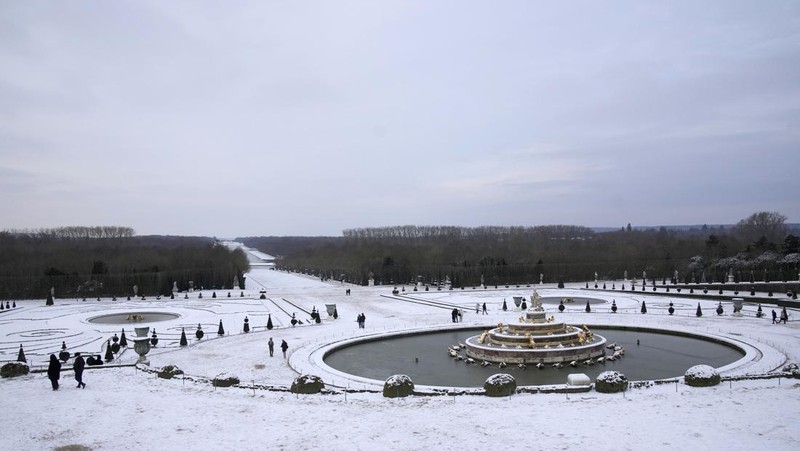 Orang-orang berjalan di gang-gang yang tertutup salju di Chateau de Versailles Selasa, 9 Januari 2024 di Versailles, sebelah barat Paris, di mana suhu turun di bawah nol derajat Celcius. (AP Photo/Christophe Ena)