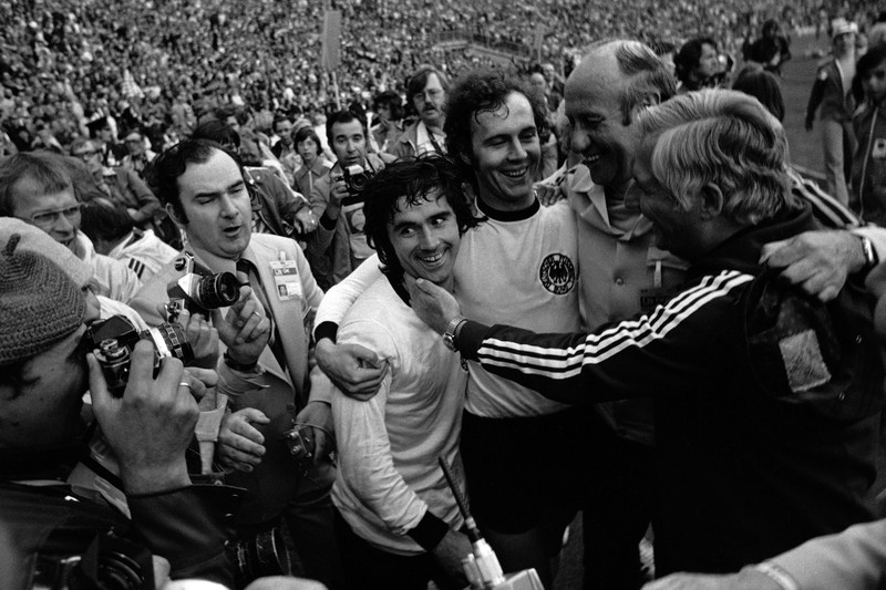 Kapten Belanda Johan Cruyff, kiri, berbicara dengan wasit, disaksikan oleh kapten Jerman Barat Franz Beckenbauer, kanan, sebelum dimulainya pertandingan sepak bola Jerman Barat v Belanda di Munich, Jerman Barat, pada 3 Juli 1984. (AP Photo/Dieter Endlicher)