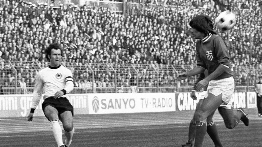 Pemain sepak bola Jerman dan kapten tim Franz Beckenbauer, kiri, menembak melewati pemain sepak bola Yunani yang tidak dikenal saat pertandingan Jerman Barat vs Yunani pada 11 November 1975 di Dusseldorf, Jerman. (AP Photo/Klaus Schlagmann)