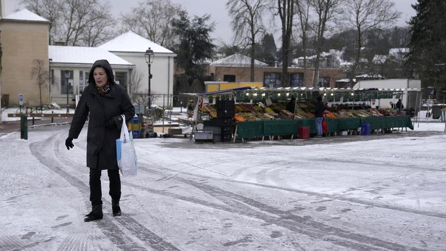 Orang-orang berjalan di gang-gang yang tertutup salju di Chateau de Versailles Selasa, 9 Januari 2024 di Versailles, sebelah barat Paris, di mana suhu turun di bawah nol derajat Celcius. (AP Photo/Christophe Ena)