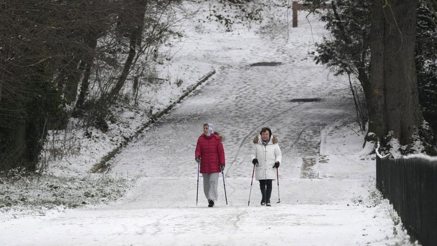 Orang-orang berjalan di gang-gang yang tertutup salju di Chateau de Versailles Selasa, 9 Januari 2024 di Versailles, sebelah barat Paris, di mana suhu turun di bawah nol derajat Celcius. (AP Photo/Christophe Ena)