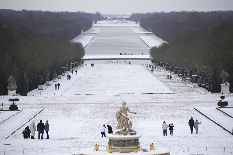 Orang-orang berjalan di gang-gang yang tertutup salju di Chateau de Versailles Selasa, 9 Januari 2024 di Versailles, sebelah barat Paris, di mana suhu turun di bawah nol derajat Celcius. (AP Photo/Christophe Ena)