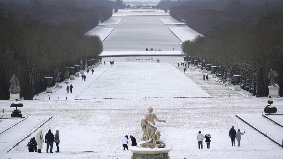 Orang-orang berjalan di gang-gang yang tertutup salju di Chateau de Versailles Selasa, 9 Januari 2024 di Versailles, sebelah barat Paris, di mana suhu turun di bawah nol derajat Celcius. (AP Photo/Christophe Ena)