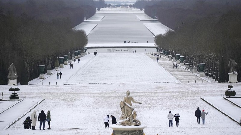 Orang-orang berjalan di gang-gang yang tertutup salju di Chateau de Versailles Selasa, 9 Januari 2024 di Versailles, sebelah barat Paris, di mana suhu turun di bawah nol derajat Celcius. (AP Photo/Christophe Ena)
