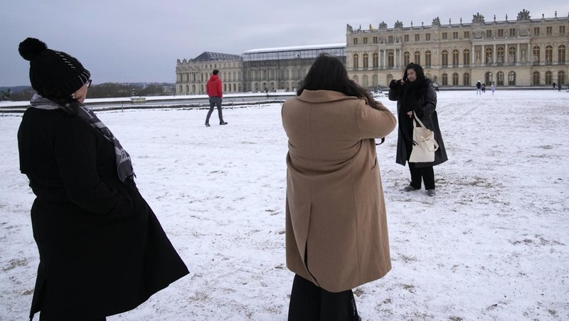 Orang-orang berjalan di gang-gang yang tertutup salju di Chateau de Versailles Selasa, 9 Januari 2024 di Versailles, sebelah barat Paris, di mana suhu turun di bawah nol derajat Celcius. (AP Photo/Christophe Ena)
