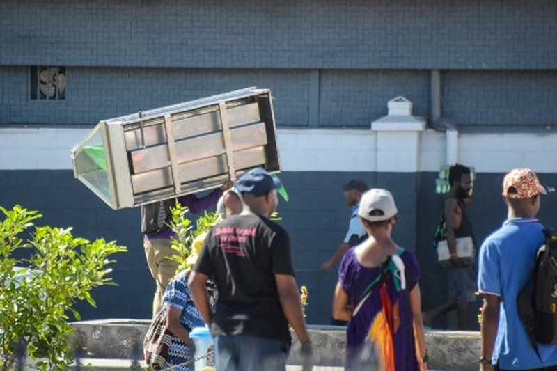 Orang-orang berkumpul di dekat sebuah gedung, di tengah laporan penjarahan dan pembakaran yang meluas ketika polisi dan sektor publik memprotes pemotongan gaji yang menurut para pejabat disebabkan oleh kesalahan administratif, di Port Moresby, Papua Nugini, 10 Januari 2024, dalam tangkapan layar yang diperoleh dari sebuah video. (Mackenzie Waide/via REUTERS)