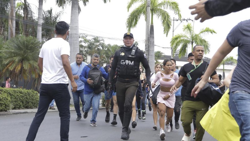 Petugas polisi menangkap salah satu pria bersenjata tak dikenal yang menyerbu ke dalam studio televisi milik negara TC saat siaran langsung, di Guayaquil, Ekuador, pada 9 Januari 2024, sehari setelah Presiden Ekuador Daniel Noboa mengumumkan keadaan darurat setelah melarikan diri dari penjara bos narco yang berbahaya. Suara tembakan terdengar di siaran langsung TV di Ekuador yang dilanda kekerasan ketika orang-orang bersenjata yang membawa senapan dan granat menyerbu studio tak lama setelah para gangster bersumpah akan melakukan 