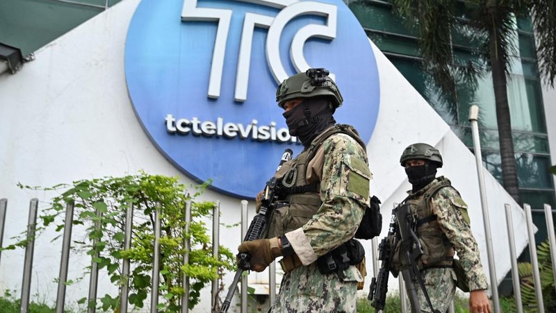 Petugas polisi menangkap salah satu pria bersenjata tak dikenal yang menyerbu ke dalam studio televisi milik negara TC saat siaran langsung, di Guayaquil, Ekuador, pada 9 Januari 2024, sehari setelah Presiden Ekuador Daniel Noboa mengumumkan keadaan darurat setelah melarikan diri dari penjara bos narco yang berbahaya. Suara tembakan terdengar di siaran langsung TV di Ekuador yang dilanda kekerasan ketika orang-orang bersenjata yang membawa senapan dan granat menyerbu studio tak lama setelah para gangster bersumpah akan melakukan 