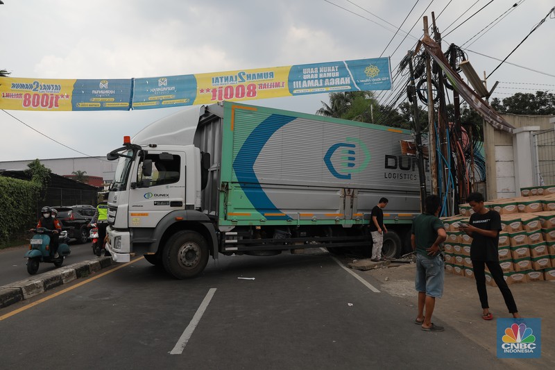 Truk bermuatan mengangkut ribuan karton Minyak Kita terjeblos, di  Jalan Raya Parung - Ciputat, Bojongsari Depok, Jawa Barat, Rabu, (10/1/2023). (CNBC Indonesia/Muhammad Sabki)
