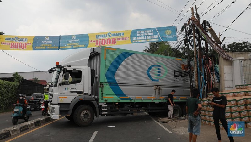 Truk bermuatan mengangkut ribuan karton Minyak Kita terjeblos, di  Jalan Raya Parung - Ciputat, Bojongsari Depok, Jawa Barat, Rabu, (10/1/2023). (CNBC Indonesia/Muhammad Sabki)
