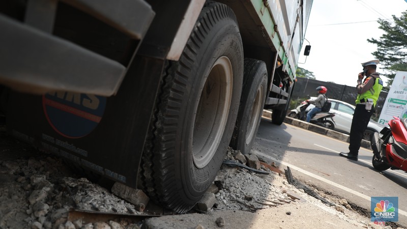 Truk bermuatan mengangkut ribuan karton Minyak Kita terjeblos, di  Jalan Raya Parung - Ciputat, Bojongsari Depok, Jawa Barat, Rabu, (10/1/2023). (CNBC Indonesia/Muhammad Sabki)