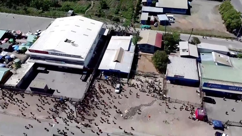 Orang-orang berkumpul di dekat sebuah gedung, di tengah laporan penjarahan dan pembakaran yang meluas ketika polisi dan sektor publik memprotes pemotongan gaji yang menurut para pejabat disebabkan oleh kesalahan administratif, di Port Moresby, Papua Nugini, 10 Januari 2024, dalam tangkapan layar yang diperoleh dari sebuah video. (Mackenzie Waide/via REUTERS)