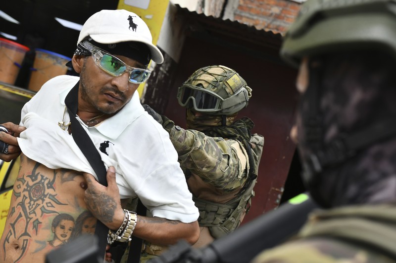 Seorang tentara memeriksa punggung seorang pria, memeriksa tato geng, selama operasi penghentian dan penggeledahan di Portoviejo, Ekuador, Kamis, 11 Januari 2024. Presiden Daniel Noboa pada Senin menetapkan keadaan darurat nasional karena gelombang kejahatan, sebuah tindakan yang memungkinkan pihak berwenang menangguhkan hak-hak masyarakat dan memobilisasi militer.  (AP Photo/Ariel Ochoa)
