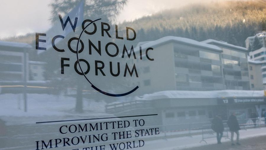 Orang-orang terpantul di kaca berlogo World Economic Forum (WEF) pada hari pertama pertemuan tahunan di Davos, Swiss, 15 Januari 2024. (REUTERS/Denis Balibouse)