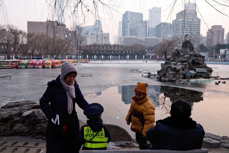 Seorang wanita dan seorang anak duduk di sebuah taman di Beijing, Cina 12 Januari 2024. (REUTERS/Tingshu Wang)