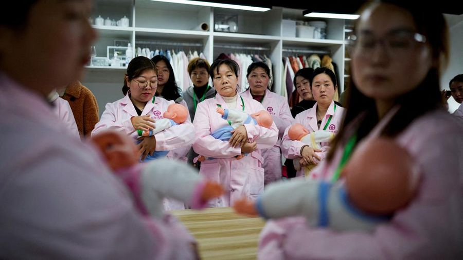 Para perempuan berlatih dengan boneka bayi plastik saat mereka mengikuti kelas keterampilan keperawatan untuk perawat kurungan, di pusat pelatihan Yipeitong di Shanghai, Tiongkok, 2 Maret 2023. (REUTERS/Aly Song/File Foto)