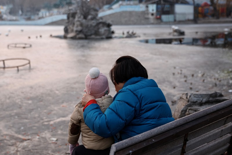 Seorang wanita dan seorang anak duduk di sebuah taman di Beijing, Cina 12 Januari 2024. Seorang wanita dan seorang anak duduk di sebuah taman di Beijing, Cina 12 Januari 2024. (REUTERS/Tingshu Wang)