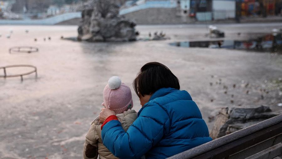 Seorang wanita dan seorang anak duduk di sebuah taman di Beijing, Cina 12 Januari 2024. (REUTERS/Tingshu Wang)