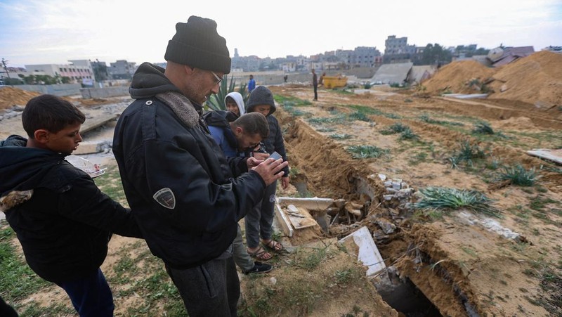 Seorang pria Palestina memeriksa kuburan yang rusak di pemakaman setelah serangan Israel, di tengah konflik yang sedang berlangsung antara Israel dan kelompok Islam Palestina Hamas, di Khan Younis di selatan Jalur Gaza, 17 Januari 2024. (REUTERS/Ahmed Zakot)