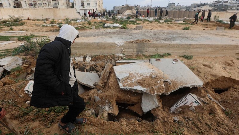 Seorang pria Palestina memeriksa kuburan yang rusak di pemakaman setelah serangan Israel, di tengah konflik yang sedang berlangsung antara Israel dan kelompok Islam Palestina Hamas, di Khan Younis di selatan Jalur Gaza, 17 Januari 2024. (REUTERS/Ahmed Zakot)