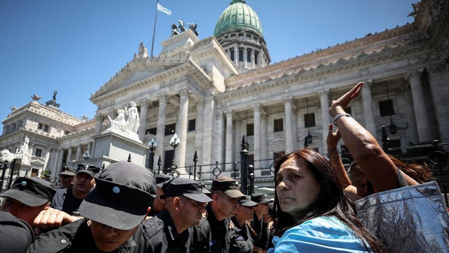 Anggota polisi berjaga di samping demonstran di luar Kongres Nasional, selama pemogokan nasional satu hari, di Buenos Aires, Argentina, 24 Januari 2024. (REUTERS/Agustin Marcarian)