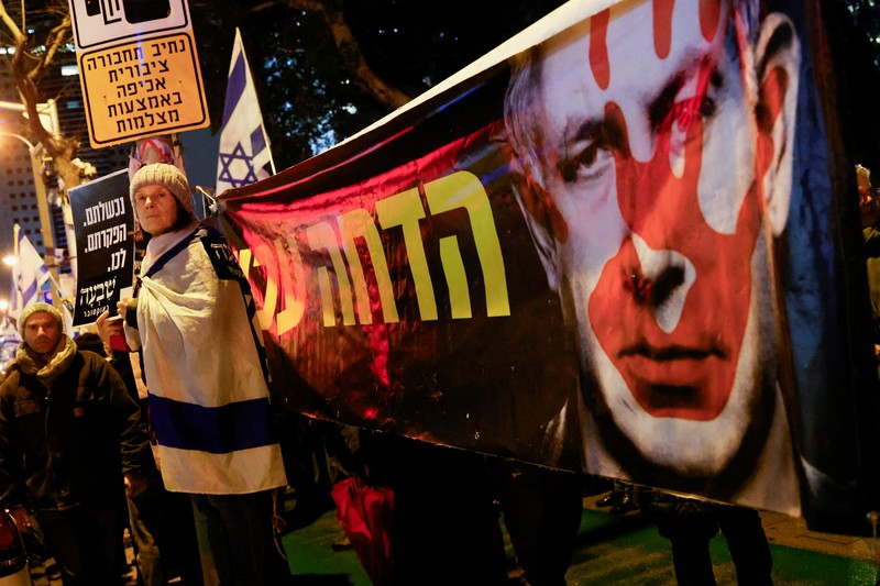 Seorang pengunjuk rasa berdiri di samping spanduk bergambar Perdana Menteri Israel Benjamin Netanyahu saat ia menghadiri rapat umum yang menuntut gencatan senjata segera di Gaza, di tengah konflik yang sedang berlangsung antara Israel dan kelompok Islam Palestina Hamas, di Tel Aviv, Israel, 27 Januari. 2024. Seorang pengunjuk rasa berdiri di samping spanduk bergambar Perdana Menteri Israel Benjamin Netanyahu saat ia menghadiri rapat umum yang menuntut gencatan senjata segera di Gaza, di tengah konflik yang sedang berlangsung antara Israel dan kelompok Islam Palestina Hamas, di Tel Aviv, Israel, 27 Januari. 2024. (REUTERS/Tyrone Siu)