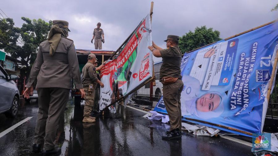 Petugas menertibkan Alat Peraga Kampanye (APK) di kawasan Jalan Raya Bogor, Kramat Jati, Jakarta, Senin (29/1/2024). (CNBC Indonesia/Faisal Rahman)