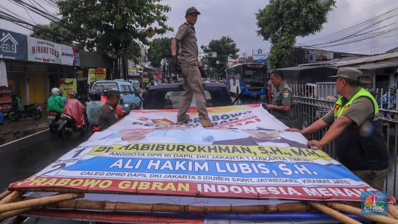 Petugas menertibkan Alat Peraga Kampanye (APK) di kawasan Jalan Raya Bogor, Kramat Jati, Jakarta, Senin (29/1/2024). (CNBC Indonesia/Faisal Rahman)