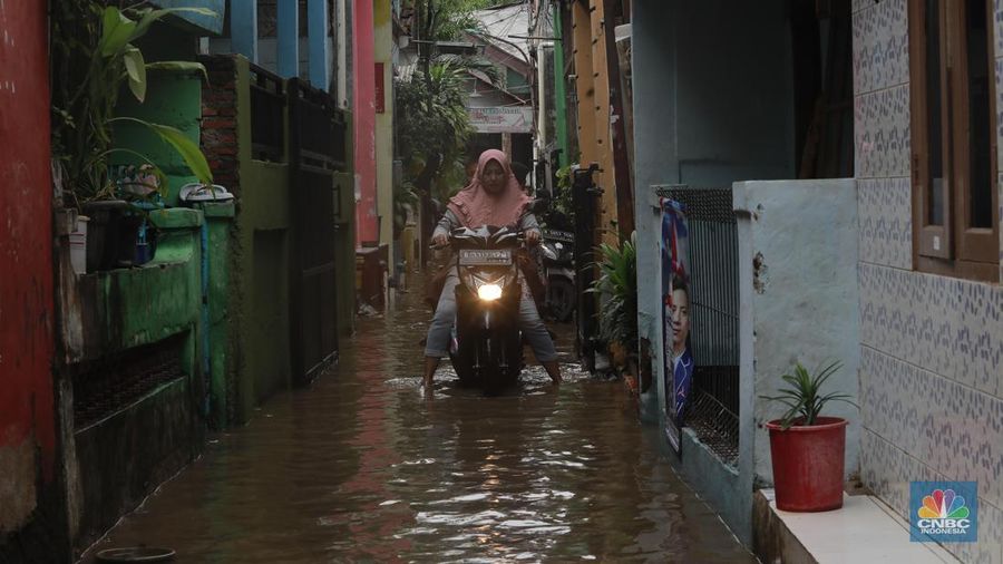 Aktifitas warga saat genangan air melanda di wilayah Cipinang Melayu, Jakarta, (31/1/2024). Pemprov DKI Jakarta melaporkan kenaikan tinggi muka air di Pos Pantau Sunter Hulu usai hujan mengguyur sejumlah wilayah di Jakarta. Pos Sunter Hulu kini statusnya naik menjadi bahaya atau Siaga 1. (CNBC Indonesia/Muhammad Sabki)