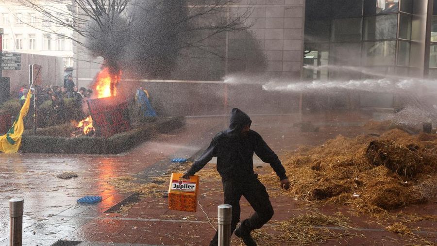 Asap mengepul dari benda-benda yang dibakar ketika orang-orang berkumpul di depan kantor pusat Uni Eropa ketika para petani Belgia menggunakan traktor mereka untuk memblokir kantor pusat, ketika mereka memprotes tekanan harga, pajak dan peraturan ramah lingkungan, keluhan yang dirasakan oleh para petani di seluruh Eropa, di Brussels, Belgia 1 Februari 2024. (REUTERS/Yves Herman)