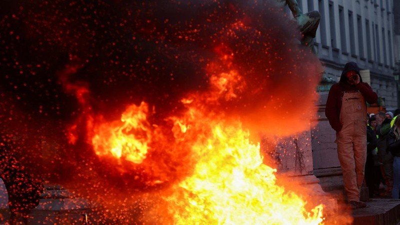 Asap mengepul dari benda-benda yang dibakar ketika orang-orang berkumpul di depan kantor pusat Uni Eropa ketika para petani Belgia menggunakan traktor mereka untuk memblokir kantor pusat, ketika mereka memprotes tekanan harga, pajak dan peraturan ramah lingkungan, keluhan yang dirasakan oleh para petani di seluruh Eropa, di Brussels, Belgia 1 Februari 2024. (REUTERS/Yves Herman)