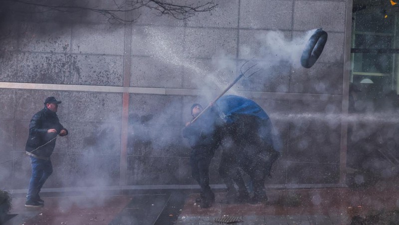 Asap mengepul dari benda-benda yang dibakar ketika orang-orang berkumpul di depan kantor pusat Uni Eropa ketika para petani Belgia menggunakan traktor mereka untuk memblokir kantor pusat, ketika mereka memprotes tekanan harga, pajak dan peraturan ramah lingkungan, keluhan yang dirasakan oleh para petani di seluruh Eropa, di Brussels, Belgia 1 Februari 2024. (REUTERS/Yves Herman)