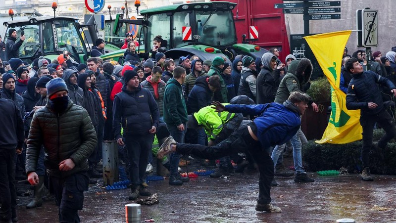 Asap mengepul dari benda-benda yang dibakar ketika orang-orang berkumpul di depan kantor pusat Uni Eropa ketika para petani Belgia menggunakan traktor mereka untuk memblokir kantor pusat, ketika mereka memprotes tekanan harga, pajak dan peraturan ramah lingkungan, keluhan yang dirasakan oleh para petani di seluruh Eropa, di Brussels, Belgia 1 Februari 2024. (REUTERS/Yves Herman)