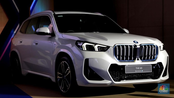 Seorang model berpose di samping mobil keluaran BMW keluaran terbaru di Ritz Carlton, Kuningan, Jakarta, Jumat, (2/2/2024). (CNBC Indonesia/Muhammad Sabki)