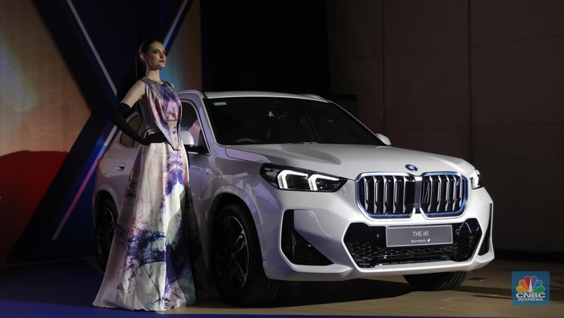 Seorang model berpose di samping mobil keluaran BMW keluaran terbaru di Ritz Carlton, Kuningan, Jakarta, Jumat, (2/2/2024). (CNBC Indonesia/Muhammad Sabki)