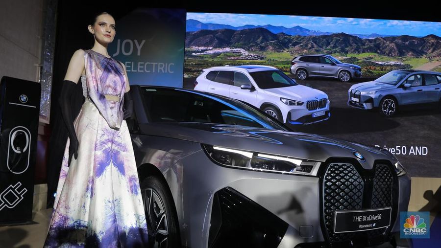 Seorang model berpose di samping mobil keluaran BMW keluaran terbaru di Ritz Carlton, Kuningan, Jakarta, Jumat, (2/2/2024). (CNBC Indonesia/Muhammad Sabki)