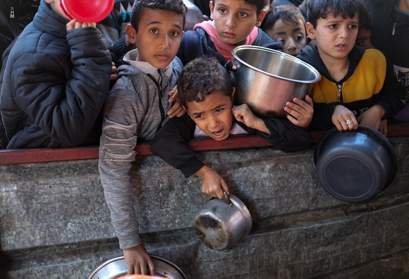 Sejumlah anak antre untuk menerima makanan pada dapur umum pengungsian di Rafah, Selatan Jalur Gaza, Senin (5/2/2024). (REUTERS/Ibraheem Abu Mustafa)