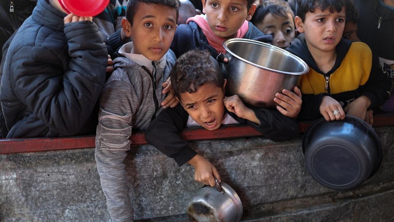 Sejumlah anak antre untuk menerima makanan pada dapur umum pengungsian di Rafah, Selatan Jalur Gaza, Senin (5/2/2024). (REUTERS/Ibraheem Abu Mustafa)