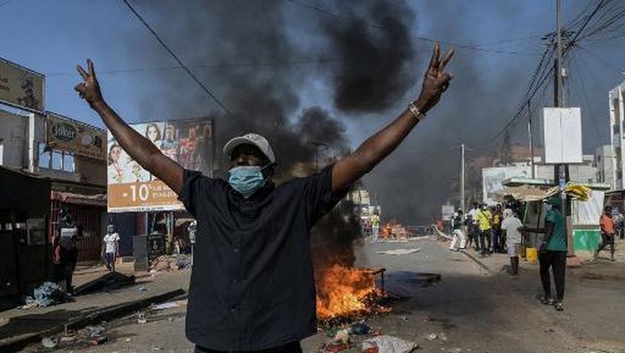 An opposition supporter reacts in front of a burning barricade during demonstrations called by the opposition parties in Dakar on February 4, 2024. Senegal police fired teargas at opposition supporters in the capital Dakar, in the first of such clashes after President Macky Sall announced the postponement of the presidential election. Senegal has been thrown into a political crisis after Sall announced on February 3, 2024 that he is postponing the presidential election that had been planned for February 25, 2024, without giving a new date. (Photo by Seyllou / AFP)