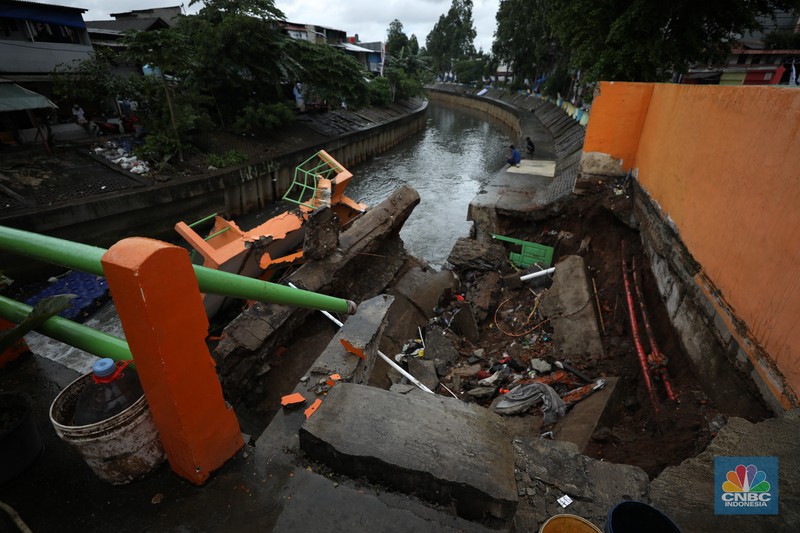 Warga mengamati Pos Pintu Air Palmerah yang jebol di kawasan Palmerah, Jakarta Barat, Selasa (6/2/2024). (CNBC Indonesia/Tri Susilo)