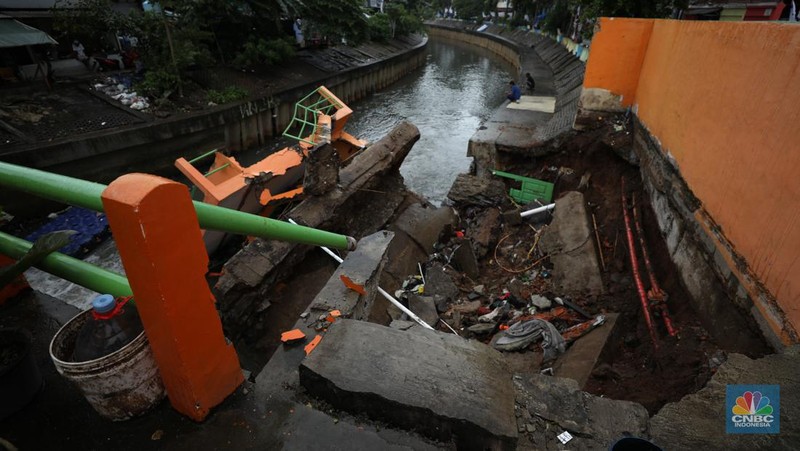 Warga mengamati Pos Pintu Air Palmerah yang jebol di kawasan Palmerah, Jakarta Barat, Selasa (6/2/2024). (CNBC Indonesia/Tri Susilo)