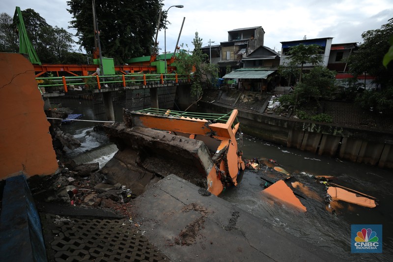 Warga mengamati Pos Pintu Air Palmerah yang jebol di kawasan Palmerah, Jakarta Barat, Selasa (6/2/2024). (CNBC Indonesia/Tri Susilo)
